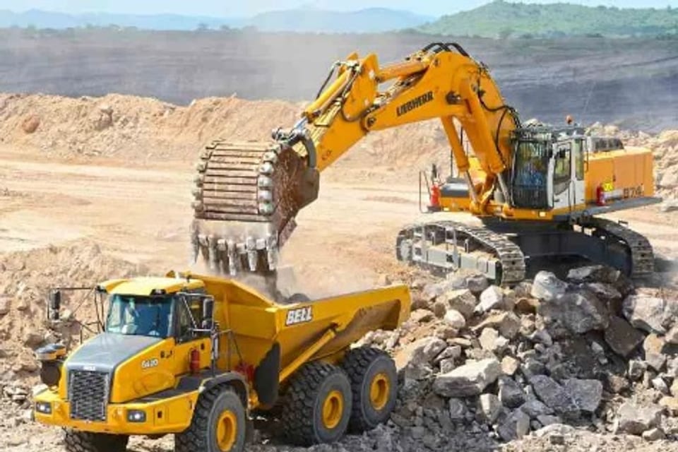 A yellow articulated dump truck being loaded by a tracked excavator on a mine site.